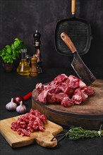 Chopping fresh beef meat for goulash or stew on wooden chopping stump