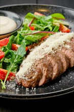 Closeup view of sliced beefsteak with parmesan and fresh vegetables