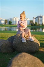 Cute little child sitting on stone in sunset time