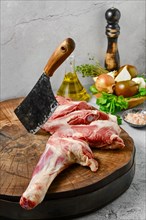 Raw lamb shoulder half cut with butcher's cleaver on wooden slab