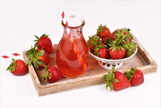 Healthy strawberry fruit lemonade in jar surrounded by berries on wooden tray