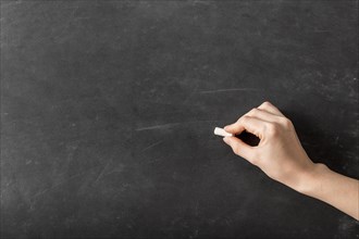 Person writing with chalk empty blackboard