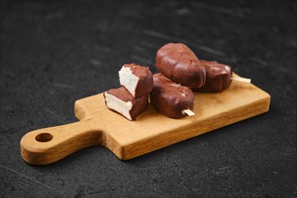 Homemade curd bars in chocolate on wooden board