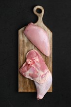 Overhead view of raw turkey leg amd breast fillet on cutting board