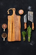 Top view of wooden cutting board with butcher tools and herbs with seasoning