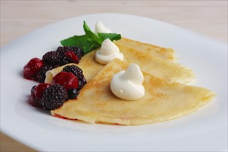 Portion on thin pancakes with sweet cream cheese and berries
