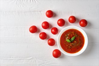 Gazpacho cold summer tomato soup with basil in a bowl on bright wooden background