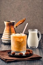 Iced coffee with fat cream on dark wooden background
