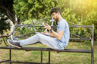 Man in a park working online with laptop. Relaxed man working with laptop outdoor