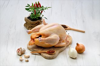 Fresh raw whole farm chicken on wooden cutting board
