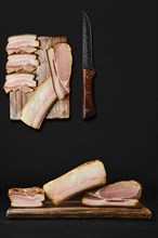 Concept for assortment of smoked pork bacon and lard on wooden cutting board