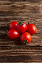 Five fresh cherry tomatoes on wooden table
