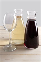 Wine glass and two pitchers with red and white wine on wooden table