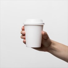 Hand holding white coffee cup close up