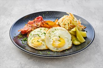 Two fried eggs with bacon and pickled cabbage with cucumber
