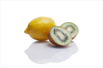 One whole lemon and two pieces of kiwi with reflection on white glass table