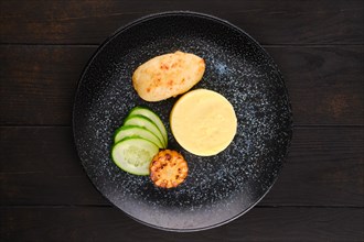 Fried chicken cutlet with mashed potato and slices of fresh cucumber and grilled corn