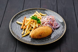 Kiev cutlet with american fries and red cabbage with carrot as a garnish