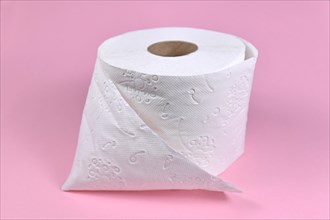 Roll of toilet paper on pink background