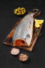 Headless fresh chinook on wooden cutting board with spice and lemon