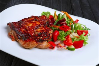 Juicy and crispy chopped pork fried on grill with fresh vegetables