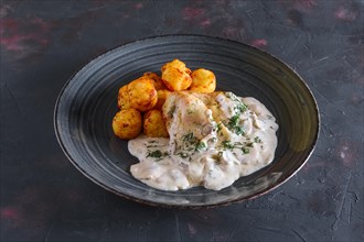 Fried potato balls and white fish fillet with creamy sauce