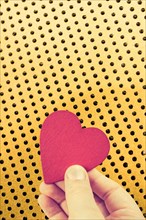 Red heart shaped object in hand as love concept