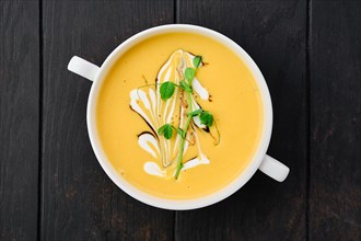 Top view of pumpkin puree soup with barbecue sauce and sour cream