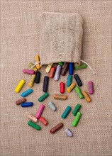 Crayons of various color out of a sack on a canvas