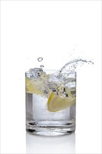 Ice cube and lemon splashing cocktail in oldfashioned glass. Drink with splashing citrus isolated on white