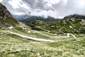 Colour reduced image of serpentine hairpin bends with approaching weather front at Colle del Nivolet