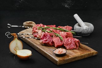 Skewers with raw beef meat and spic on dark background