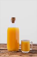 Fresh orange juice in bottle and mug on wooden table