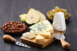 Assortment of cheese and snack for wine on dark wooden table