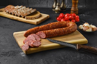 Smoked beef sausage rings on wooden cutting board on kitchen table