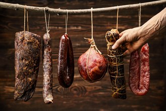 Assortment of dried meat and sausages hanging on a stick in a barn