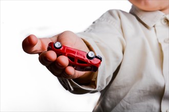 Baby hand holding a red car on a white background
