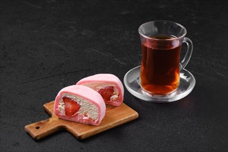 Sweet dessert mochi with strawberry cut on half with fruit tea