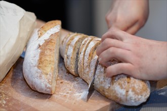 Cutting healthy bread with seeds on wooden board with a knife