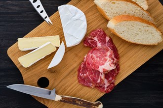 Overhead view of camembert sandwich with smoked bacon on dark wooden table