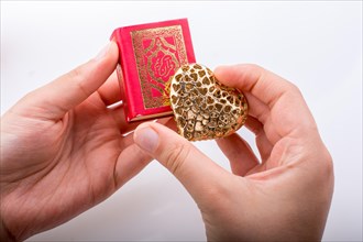 Hand holding Heart shape and Islamic Holy Book Quran