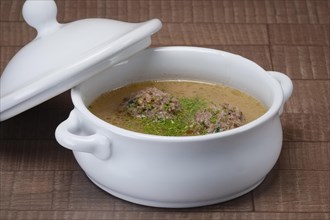 Tureen with meatballs soup sprinkled with dill