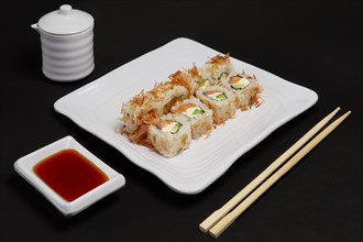 Portion of bonito rolls served on plate with soy sauce and wooden hashi