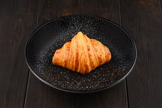 Freshly baked big croissant on a plate