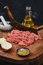 Making fresh raw minced meat with vintage chopping knife on wooden log