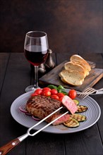 Grilled beef steak and zucchini served with fresh tomato cherry and basil and a glass of red wine