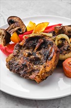 Lamb neck with champignon and vegetables baked in oven on a plate