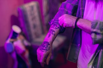 Close up man with tattoo his hand folding shirt sleeves