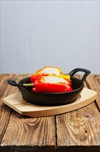Bell pepper stuffed with meat with melted cheese mozzarella on top baked in oven in cast iron skillet. Top view. Natural wooden background