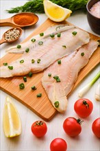 Raw fresh haddock fillet on wooden cutting board with spice and herbs